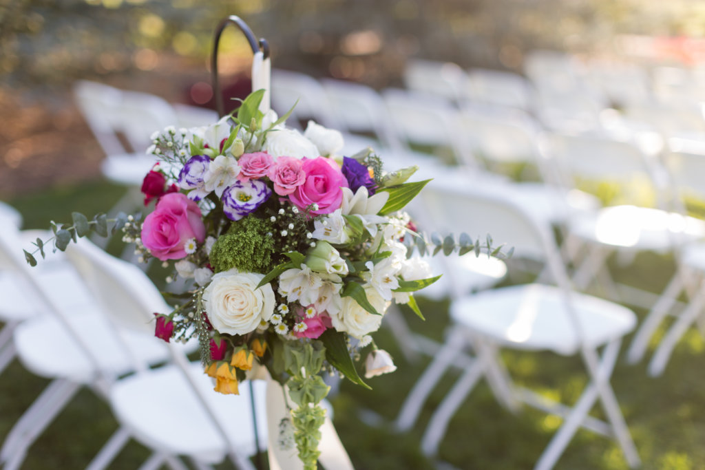 A bouquet of flowers arranged by chairs at an outdoor wedding ceremony.