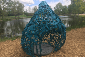 Recycled small pieces of steel scrap, painted blue and shaped to look like a large water droplet with an opening in one side so that people can crawl in and out of the sculpture