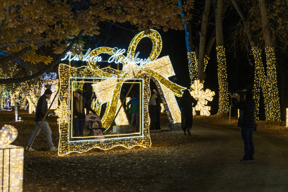 Couple with baby posing in lighted "Hudson Holidays" frame