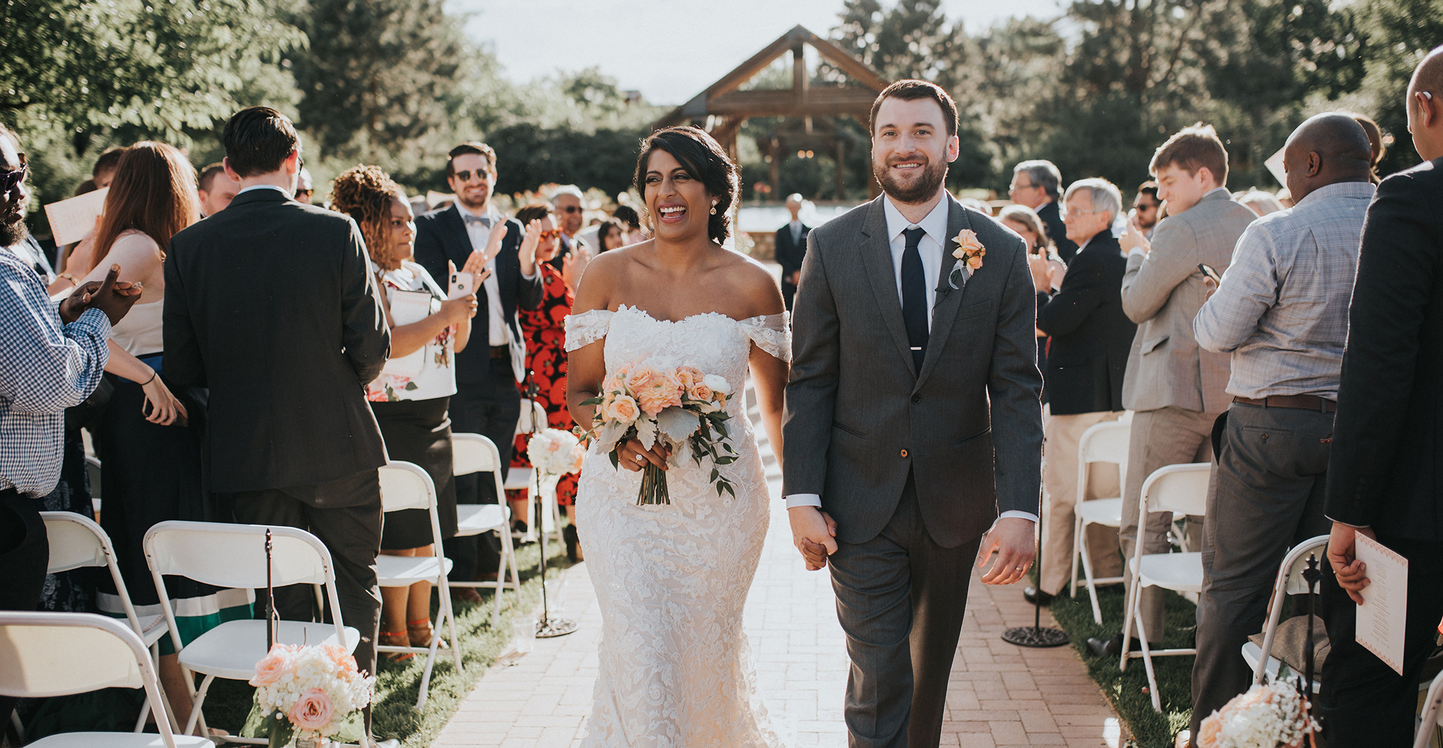 a bride and groom walk down the aisle at a rose garden wedding ceremony near Denver Colorado