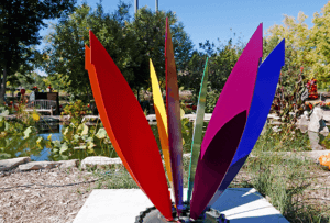 Steel sculpture of a lotus plant, but each leaf is a different color of the rainbow