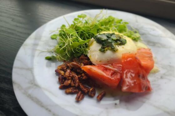 A small plate featuring a salad, some cabdied nuts and a portion of fruit