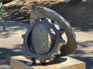 Stobe sculpture representing two gears leaned on opposite sides of a stone wheel