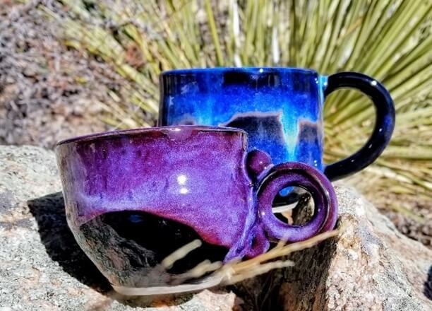 Two handmade coffee mugs on a natural backdrop.